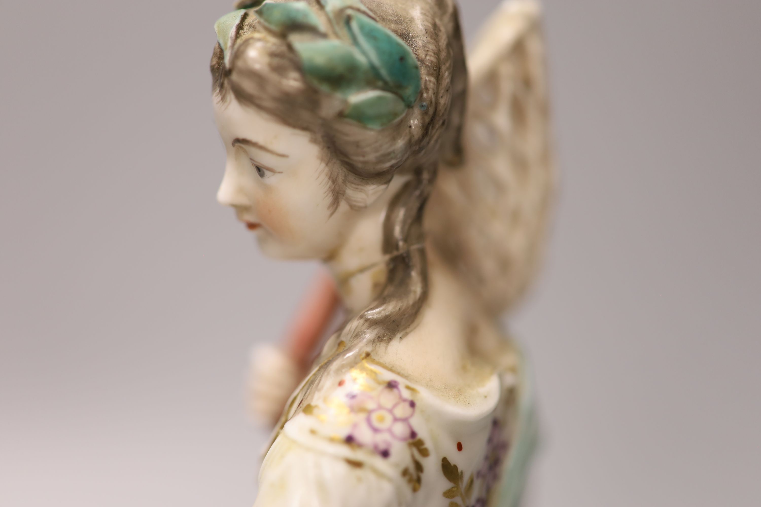 A Derby figure of Water, modelled as a girl holding a fish net her apron holding three fish, stand on a naturalistic beside a black lob